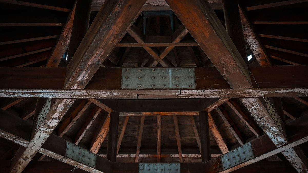 Charpente traditionnelle en bois massif visible sous une couverture déposée