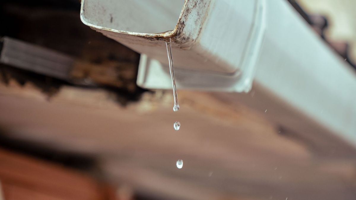 Gouttière en zinc en fin de pluie, goutte d'eau suspendue au bord